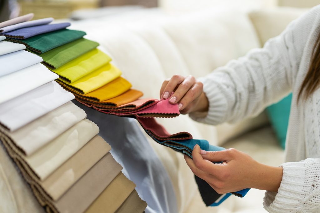 The woman chooses the fabric on the sofa. Textile industry background. Tissue catalog